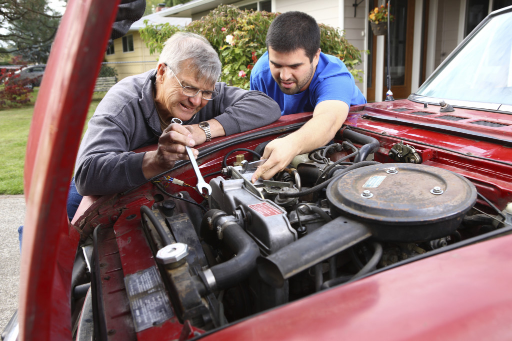 Senior man and son working on car engine